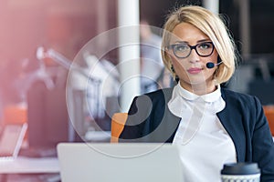 Customer service representative at work. Beautiful young woman in headset working at the computer