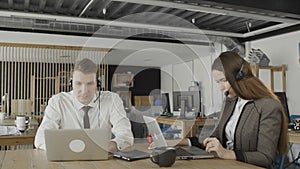 Customer service woman and man operators taking calls in busy call center