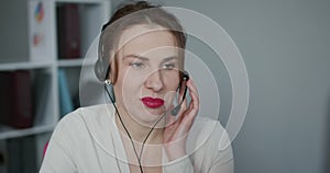 Customer support agent or call center with headset works on desktop computer while supporting the customer on phone call