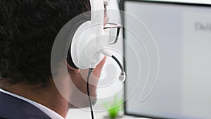 customer support, black man with a headset works as a call center operator sitting at a monitor at home