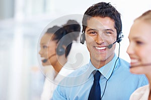 Customer support. Portrait of smiling male representative with employees at call center.