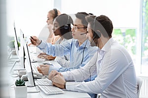 Customer support service. Hotline operator helping his colleague at call centre office