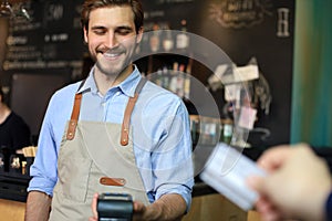 Customer using credit card for payment to owner at cafe restaurant, cashless technology