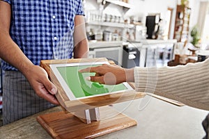 Customer using touch screen sales terminal at cafe, close up