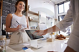 Customer using touch screen to make payment at a coffee shop