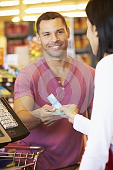 Customer Using Vouchers At Supermarket Checkout