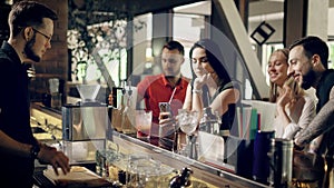 Customers in the bar watching bartender doing fresh cocktail. Close up of hands of a barman preparing beverages for