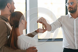 Customers bought the place, receiving the keys. Realtor shows an apartment to a young couple photo