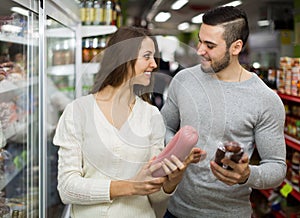 Customers near fridge with meat products