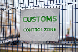 Customs control zone sign on metal fence, border symbol