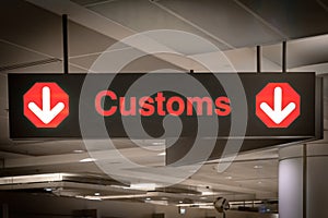 Customs sign in Airport and direction arrow, red and lighted.