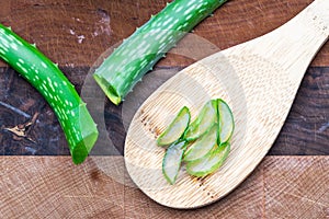 Cut Aloe Vera Leaf on wooden background with spatula