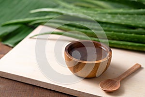 Cut aloe vera stem and gel in wooden bowl on wooden background