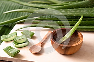 Cut aloe vera stem and gel in wooden bowl on wooden background