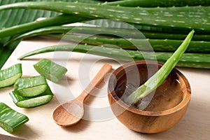 Cut aloe vera stem and gel in wooden bowl on wooden background, healthy food drink and skin care for beauty concept, copy space