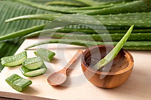 Cut aloe vera stem and gel in wooden bowl on wooden background, healthy food drink and skin care for beauty concept, copy space