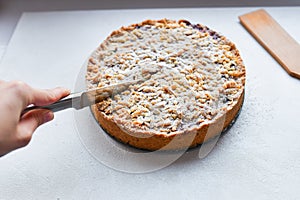 cut berry pie. slice of homemade sour cherry pie on plate and whole tart cut in slices in baking dish on napkin on wooden table,