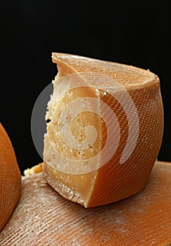 Cut block of aged cheese over black background