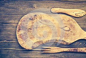 Cut board and other kitchen utensils on wooden background