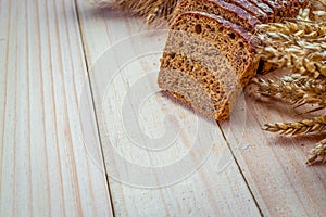 Cut bread. Fresh loaf of rustic traditional bread with wheat grain ear or spike plant on wooden texture background. Rye