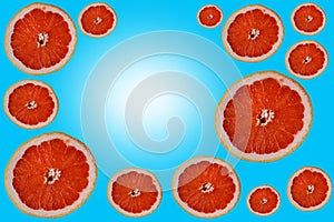 Cut bright red orange halves grapefruit slices on colorful light blue sky turquoise gradient backdrop