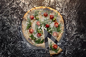 Cut cheese pizza with flour on dark concrete background top view