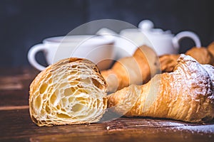 A cut croissant and a croissant with sugar powder lie side by side.