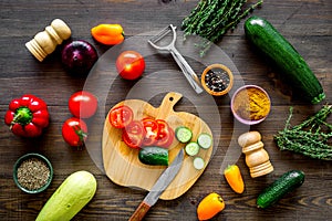 Cut different fresh vegetables on cutting board for cooking vegetable stew. Dark wooden background top view