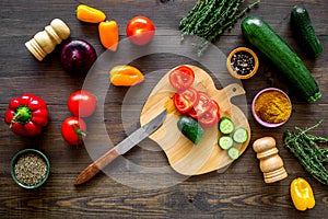 Cut different fresh vegetables on cutting board for cooking vegetable stew. Dark wooden background top view