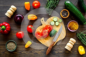 Cut different fresh vegetables on cutting board for cooking vegetable stew. Dark wooden background top view