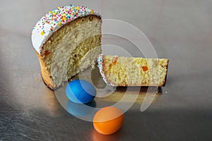 Cut Easter cake with multi-colored topping and dried fruits filling among colored Easter eggs