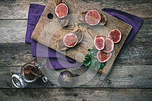 Cut figs and bread with jam on choppingboard in rustic style