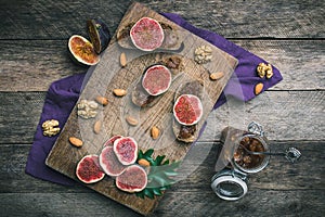 Cut figs, nuts and bread with jam on choppingboard in rustic sty