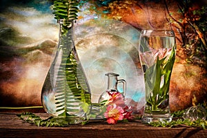 Cut flowers and tropical plants in a glass of water on a barn wood table