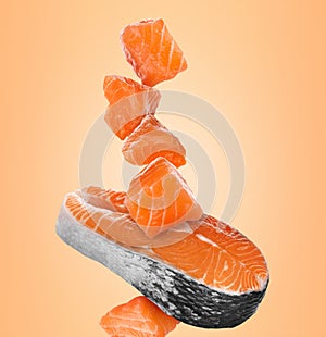 Cut fresh salmon falling on pale orange background