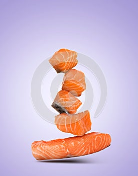 Cut fresh salmon falling on violet gradient background