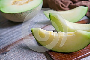 Cut of fresh sweet green melon on the wooden background. Fruits or healthcare concept. Selective focus, close up