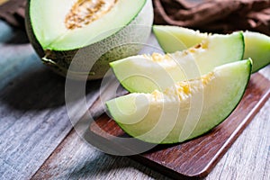 Cut of fresh sweet green melon on the wooden table. Fruits or healthcare concept. Selective focus, close up