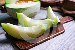 Cut of fresh sweet green melon on the wooden table. Fruits or healthcare concept. Selective focus, close up