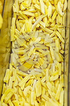 Cut frozen French fries in a refrigerator in a supermarket. Close-up. Health and ready-made semi-finished products. Vertical
