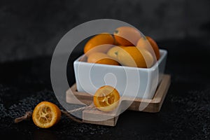 Cut fruit kumquat on a black background, citrus