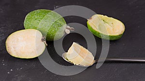 Cut fruit of the mature feijoa on a dark slate background. Pulp fruit on the bark spoon