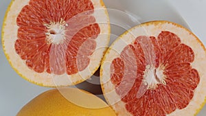 Cut in half grapefruit spins in a circle on a white background. Top view.