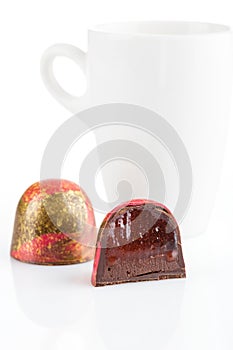 Cut handmade candy with with chocolate ganache and red confiture on white background. Exclusive handcrafted bonbon