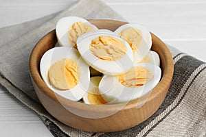 Cut hard boiled chicken eggs in bowl on table