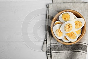 Cut hard boiled chicken eggs in bowl on wooden table, flat lay. Space for text