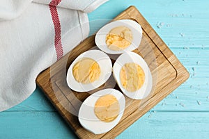 Cut hard boiled chicken eggs on blue wooden table, flat lay