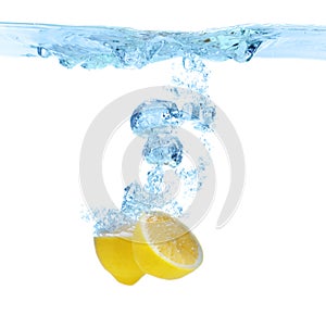 Cut lemon falling down into clear water against background