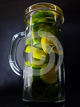 Cut lime in the jar on black background