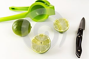 Cut limes with juicer and knife isolated on white